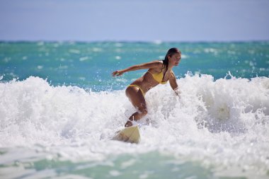 Girl in a yellow bikini surfing clipart