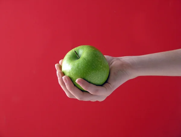 Manzana en mano sobre rojo —  Fotos de Stock