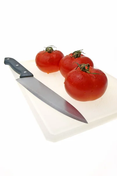 stock image Cutting white plastic board with a knife and tomato