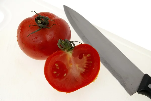 stock image Cutting white plastic board with a knife and tomato