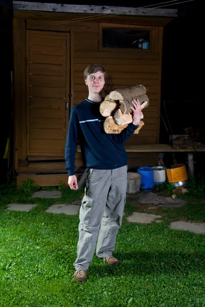 De jonge staande man met brandhout - Stok İmaj