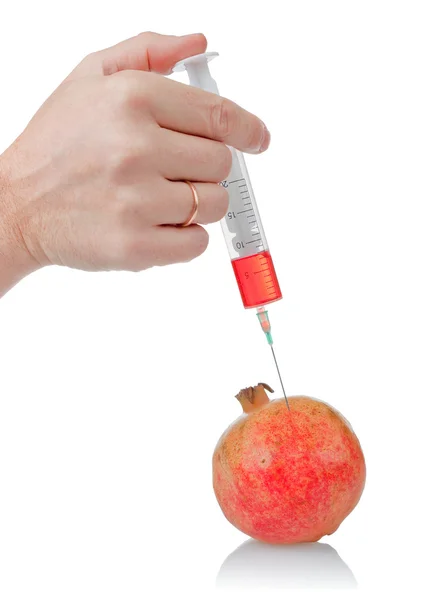 Hand holds the syringe on pomegranate — Stock Photo, Image