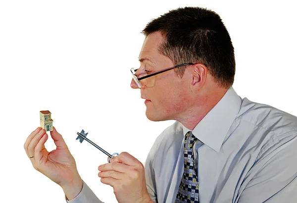 Человек с игрушечным домиком и ключом — стоковое фото