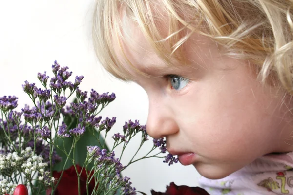 Kleines Mädchen, das Blumen riecht — Stockfoto