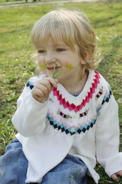 The little girl sniffing flowers — Stock Photo, Image