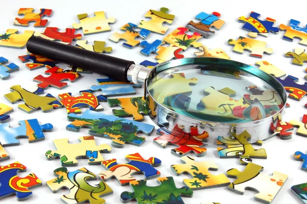 Zvětšovací sklo a puzzle — Stock fotografie