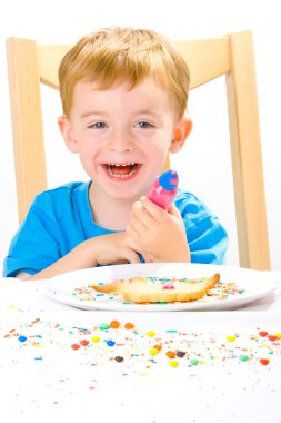 Boy decorating baked biscuits clipart