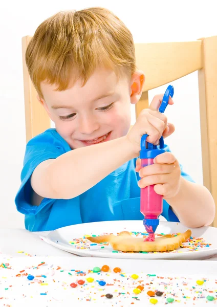 Chlapec zdobení upečené sušenky — Stock fotografie