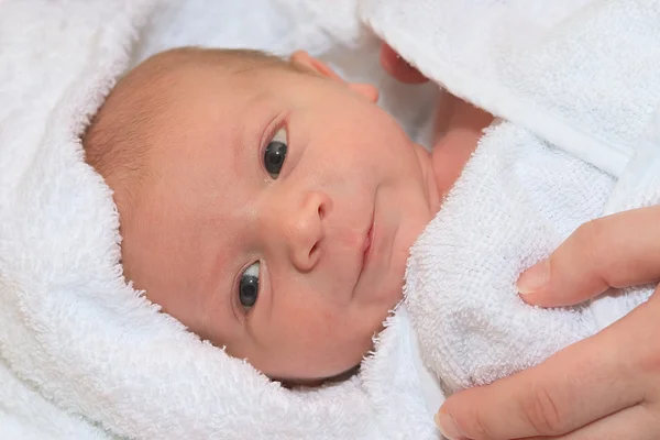 Baby kuschelt sich nach einem Bad ins Handtuch — Stockfoto