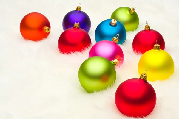 Many Christmas baubles on white fur — Stock Photo, Image