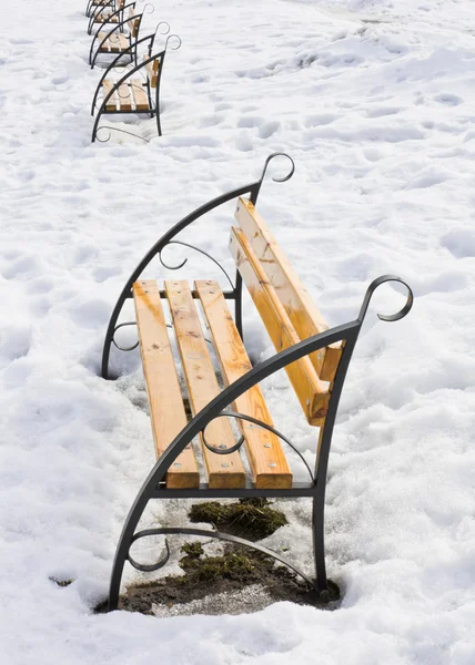 Light brown wooden benches on snow — Stock Photo, Image