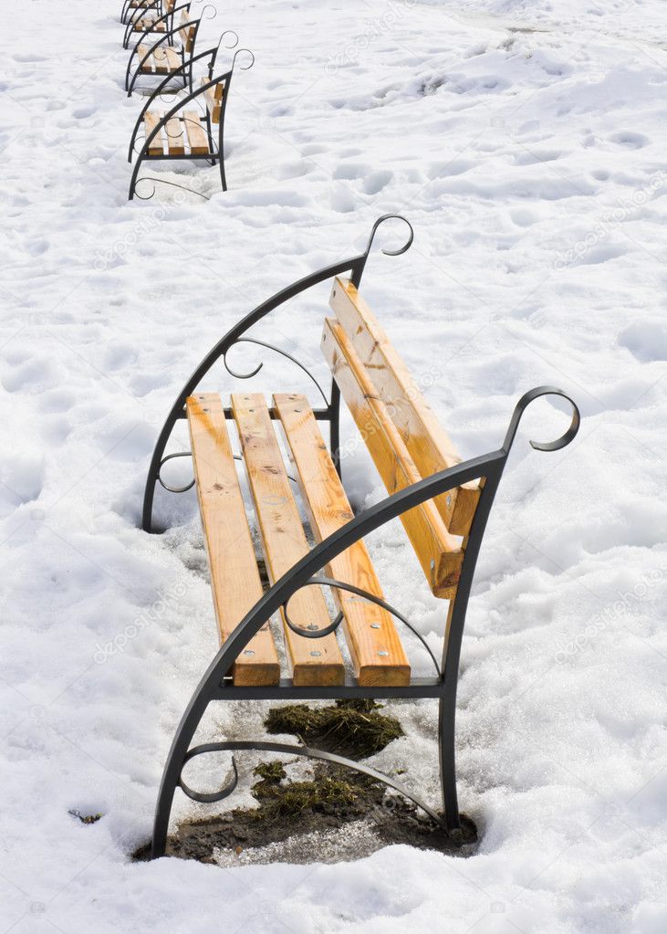 Light brown wooden benches on snow