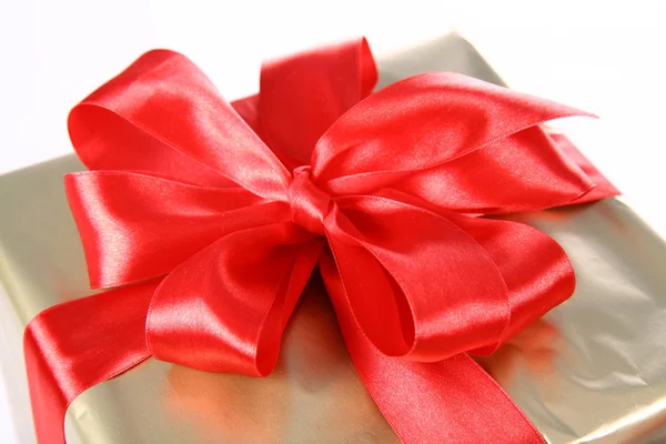 Подарок в золотой упаковке с красным бантом — стоковое фото