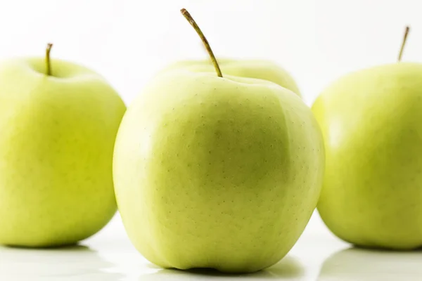 One green apple in front of three — Stock Photo, Image