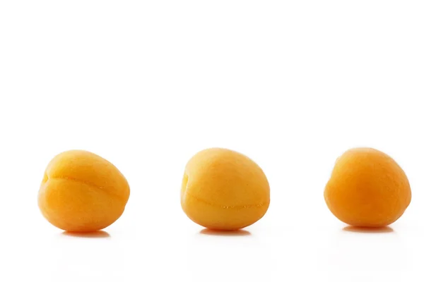 Drie abrikozen in een rij — Stockfoto