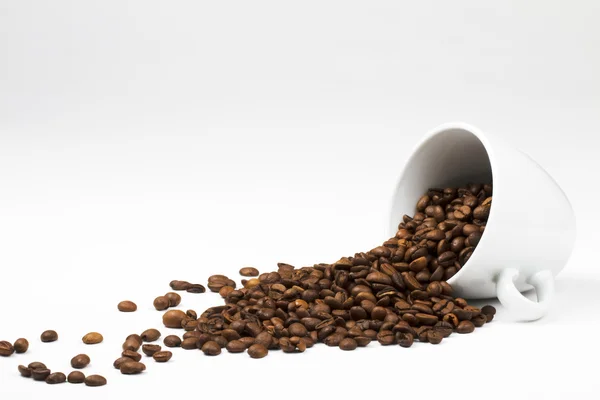 Granos de café cayendo de taza de café — Foto de Stock