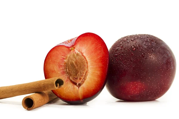 Wet plum and a half and two cinnamon sticks — Stock Photo, Image