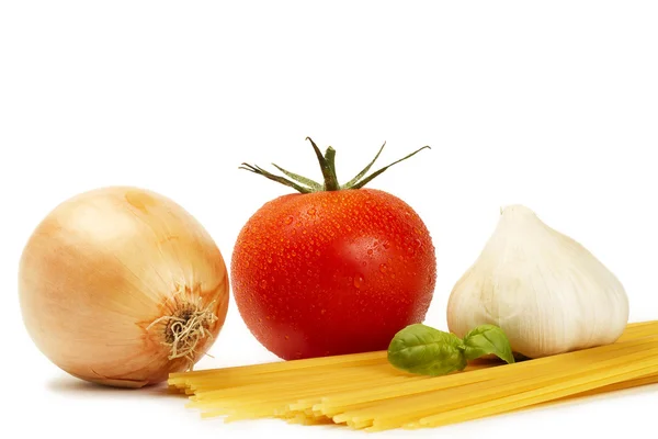 Сырые спагетти с помидорами, базиликом, чесноком и луком — стоковое фото