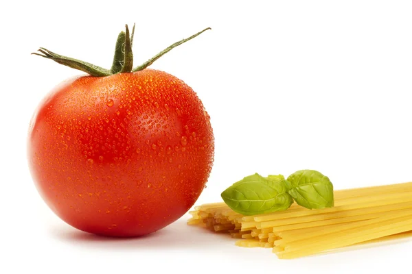 Сырые спагетти с помидорами и базиликом — стоковое фото
