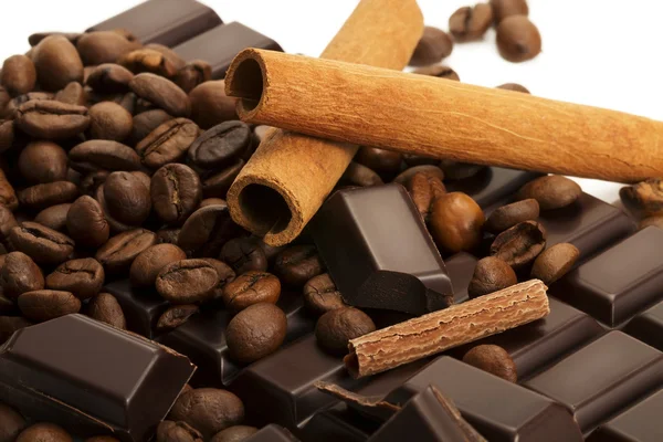 Кофейные зерна на шоколадной плитке с коричными палочками — стоковое фото