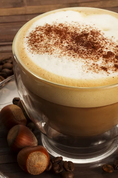 Cappuccino mit Haselnüssen auf Holzgrund — Stockfoto