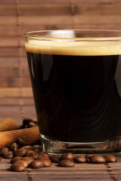 Espresso i en kort glas med kaffebönor och kanel från sidan — Stockfoto