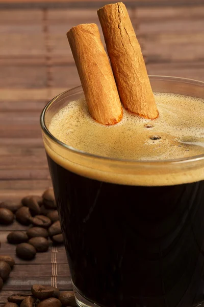 Palitos de canela dentro de espresso en un vaso corto — Foto de Stock