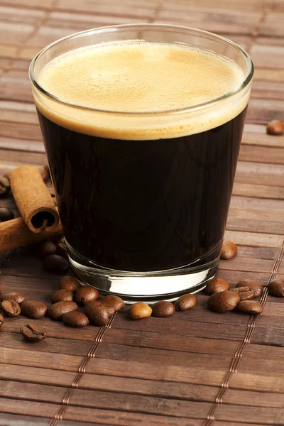 Espresso in a short glass with coffee beans and cinnamon from diagonal top — Stock Photo, Image