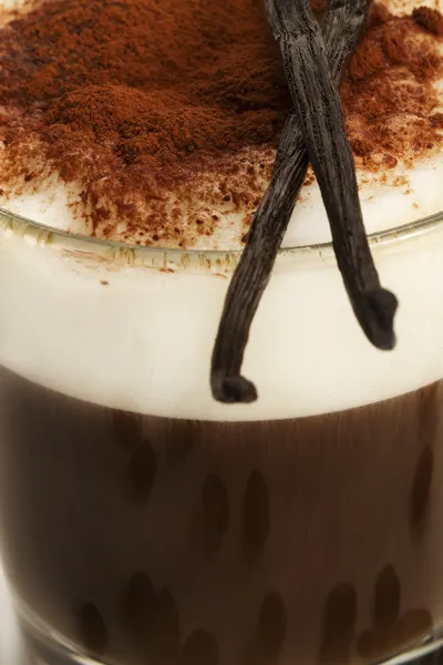 Primer plano del café con espuma de leche cacao en polvo con granos de vainilla —  Fotos de Stock