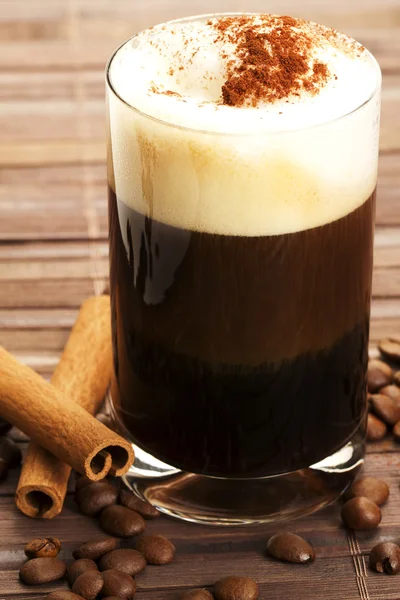 Espresso con espuma de leche cacao en polvo y palitos de canela — Foto de Stock