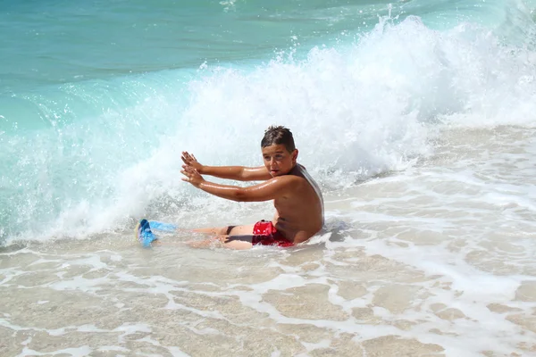 Mały chłopiec siedzi i zatrzymanie fale na morzu — Zdjęcie stockowe