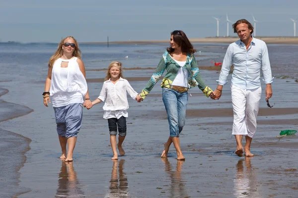 Familia padres niña niños caminando en la playa 