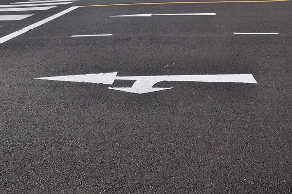 Due frecce dirette sulla strada asfaltata — Foto Stock