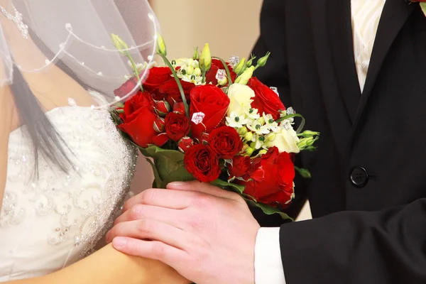 Braut und Bräutigam mit rotem Rosenstrauß — Stockfoto