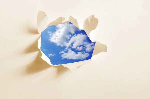Облачное небо за бумажной дырой — стоковое фото