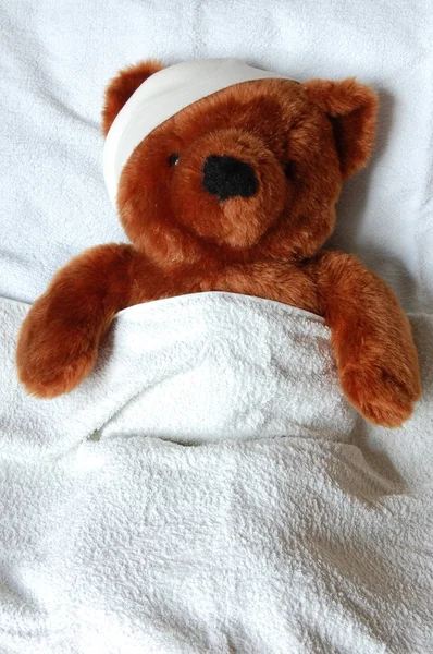 Sick teddy with injury in bed — Stock Photo, Image