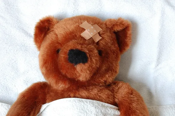 Nemocný medvídek s poranění v posteli — Stock fotografie
