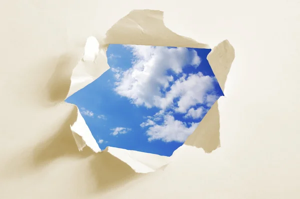 Bewolkte hemel achter papier gat — Stockfoto