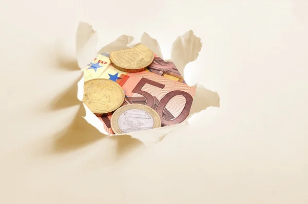 Dinheiro do euro atrás do buraco no papel — Fotografia de Stock