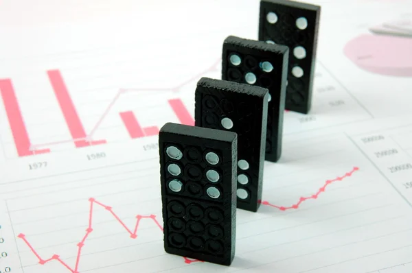 Risky domino over a financial business chart — Stock Photo, Image