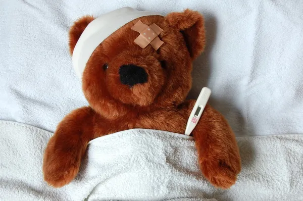 Больной Тедди с травмой в постели — стоковое фото