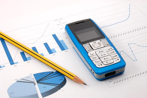 Mobilní telefon přes obchodní graf — Stock fotografie