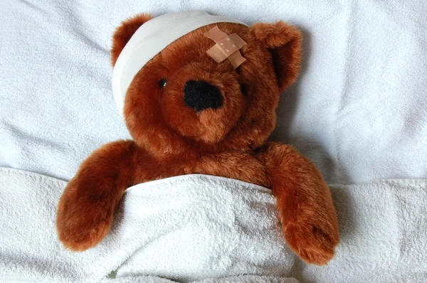 Sick teddy with injury in bed Stock Photo