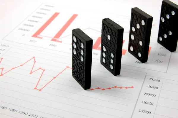 Risky domino over a financial business chart — Stock Photo, Image