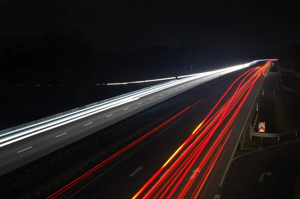Estrada com trânsito de carro à noite com luzes embaçadas — Fotografia de Stock