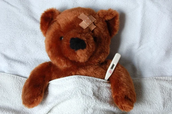 Ziek teddy met letsel in bed — Stockfoto