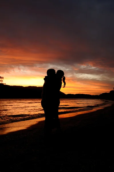 Casal backlit beijos no romântico por do sol Imagens De Bancos De Imagens
