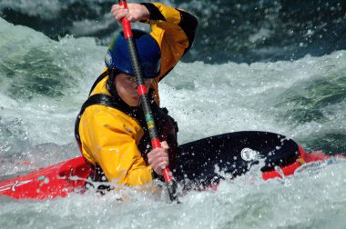 fighting the rapids of a river in a kayak clipart