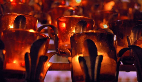 stock image Church candles in red and yellow transparent chandeliers