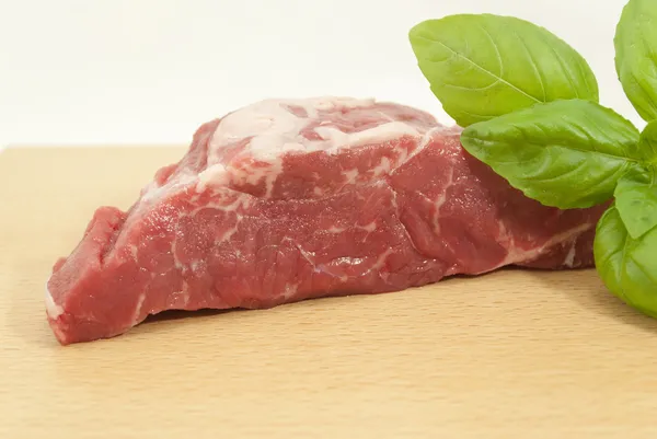 Pedaço de carne com folhas de manjericão — Fotografia de Stock